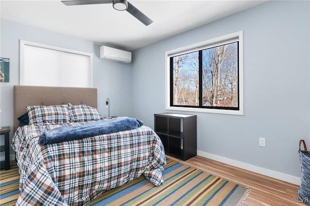 bedroom with ceiling fan, a wall mounted air conditioner, and light hardwood / wood-style flooring