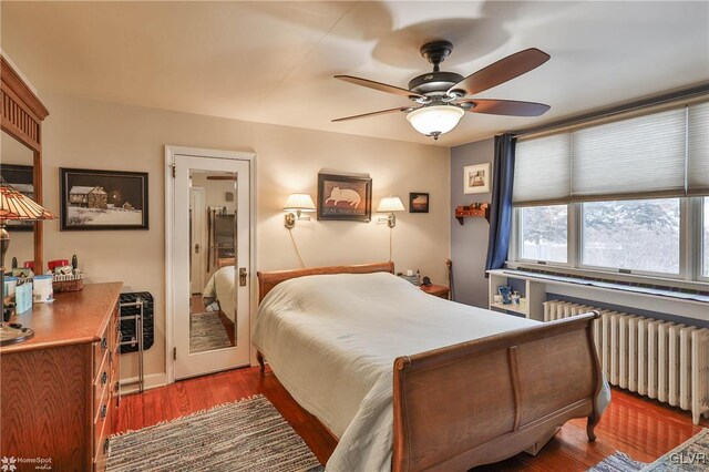 bedroom with ceiling fan, radiator heating unit, and dark hardwood / wood-style flooring