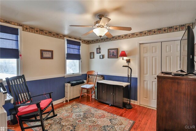 living area with radiator, wood-type flooring, and ceiling fan