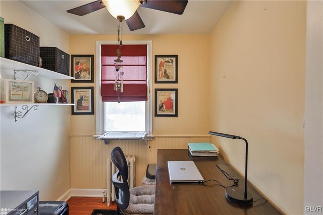 office featuring ceiling fan, wood-type flooring, radiator heating unit, and wood walls