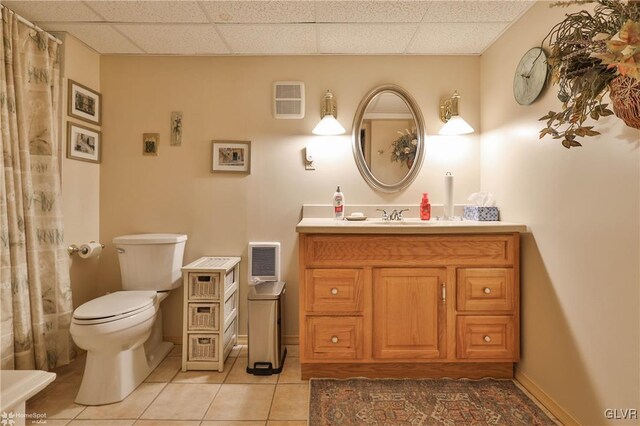 bathroom with vanity, toilet, tile patterned flooring, and a drop ceiling