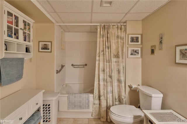 bathroom with tile patterned flooring, a paneled ceiling, shower / bath combination with curtain, and toilet