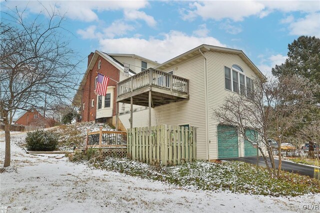 view of snowy exterior featuring a garage and a deck