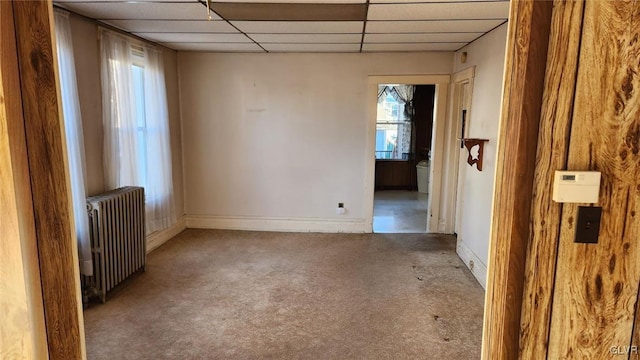 spare room with radiator, light carpet, and a drop ceiling