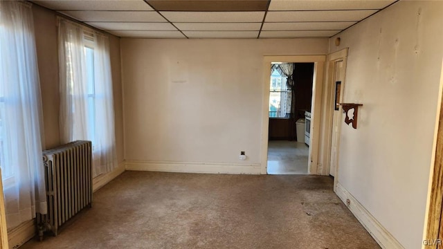 carpeted empty room with a drop ceiling and radiator