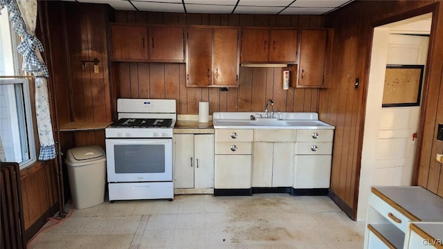 kitchen featuring sink, radiator, a paneled ceiling, white range with gas cooktop, and wood walls