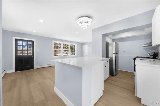 kitchen with white cabinetry, a baseboard heating unit, a wealth of natural light, and stainless steel fridge