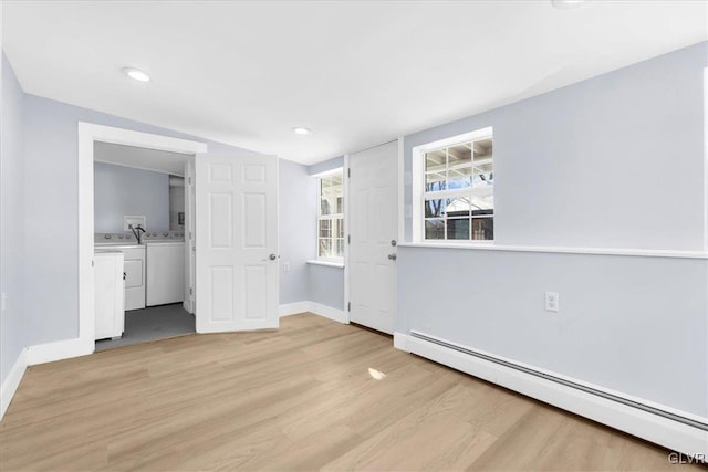 interior space featuring a baseboard heating unit, light hardwood / wood-style flooring, and independent washer and dryer