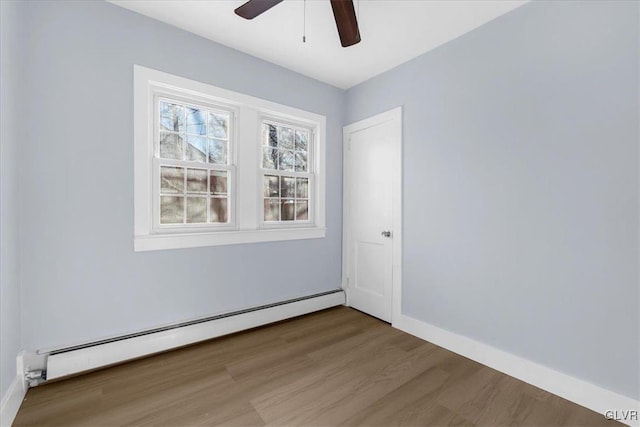 spare room featuring wood-type flooring, ceiling fan, and baseboard heating