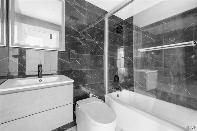 full bathroom featuring vanity, tile walls, shower / bath combination with glass door, and toilet