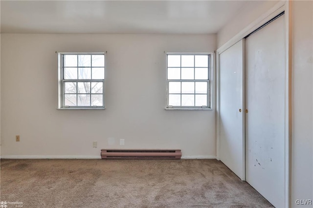 interior space featuring multiple windows, a baseboard heating unit, and light colored carpet