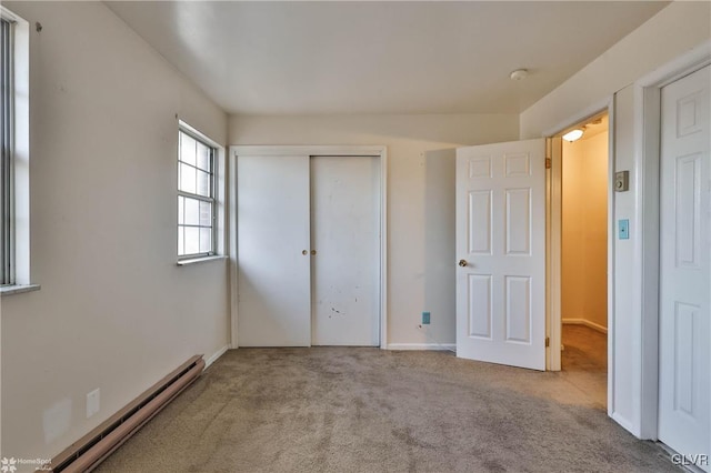 unfurnished bedroom featuring a baseboard radiator, light colored carpet, and a closet