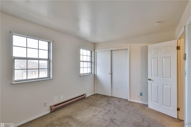 unfurnished bedroom with a baseboard heating unit, light colored carpet, and a closet