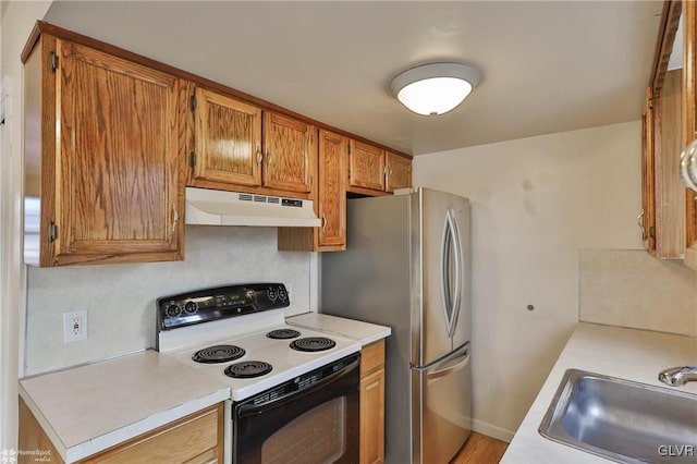 kitchen featuring stainless steel refrigerator, sink, and electric range