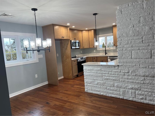 kitchen featuring appliances with stainless steel finishes, dark hardwood / wood-style flooring, kitchen peninsula, and hanging light fixtures