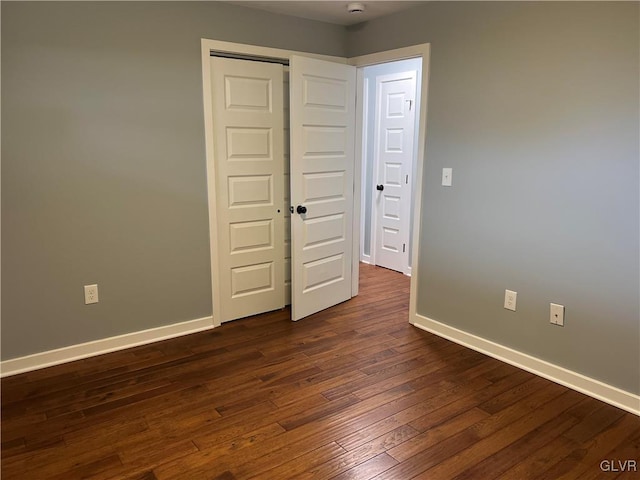 unfurnished bedroom with dark wood-type flooring and a closet