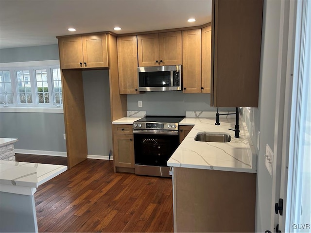 kitchen featuring light stone counters, stainless steel appliances, sink, and dark wood-type flooring