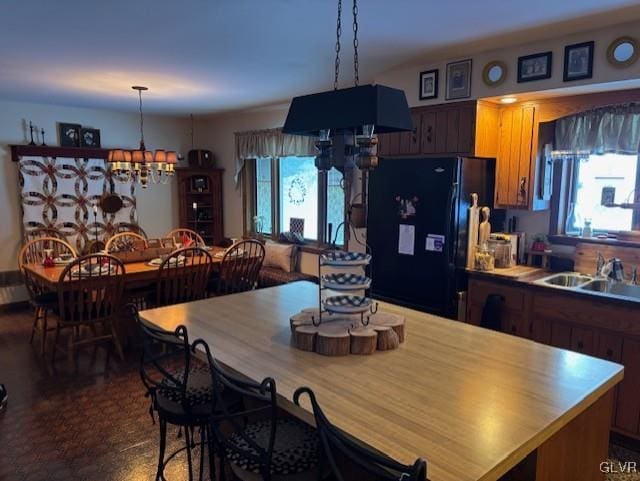 kitchen with black refrigerator, an inviting chandelier, and sink