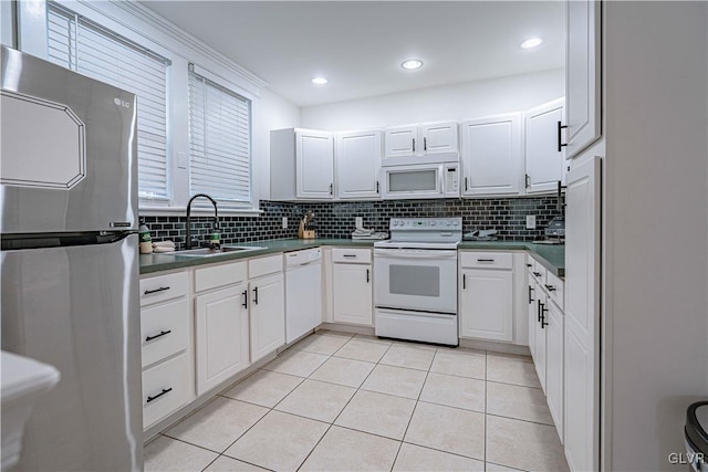 kitchen featuring sink, white appliances, light tile patterned floors, backsplash, and white cabinets