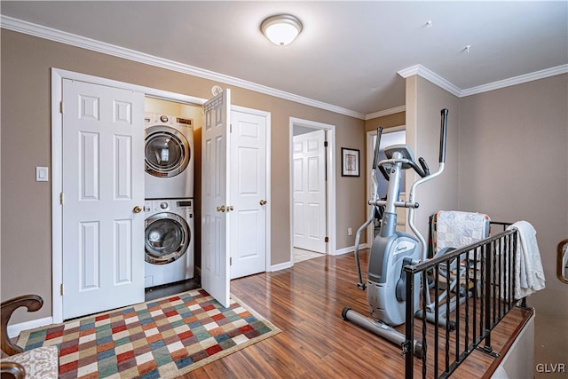 laundry room featuring hardwood / wood-style flooring, stacked washing maching and dryer, and crown molding