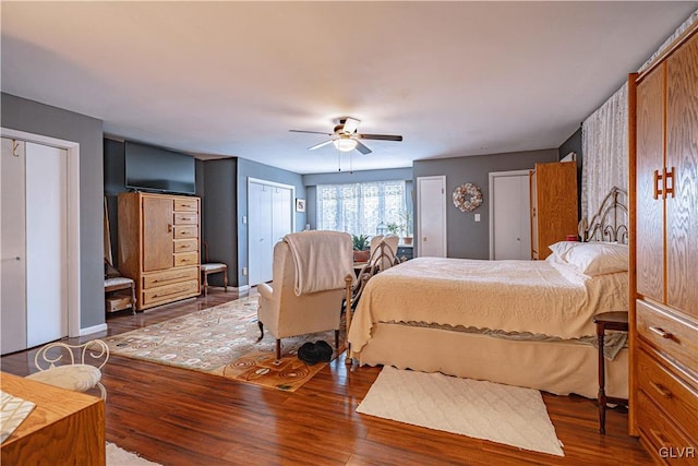 bedroom with multiple closets, ceiling fan, and dark hardwood / wood-style flooring