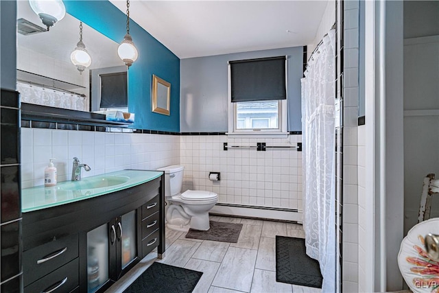 bathroom with vanity, tile walls, baseboard heating, and toilet