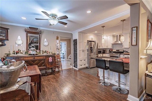 kitchen with white cabinetry, dark hardwood / wood-style flooring, hanging light fixtures, stainless steel appliances, and wall chimney range hood