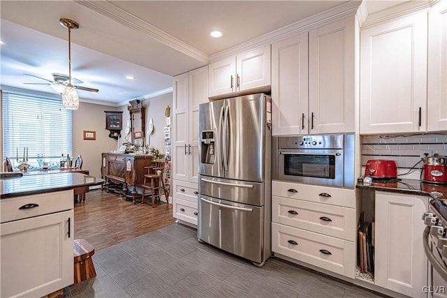 kitchen featuring ceiling fan, stainless steel appliances, tasteful backsplash, ornamental molding, and white cabinets