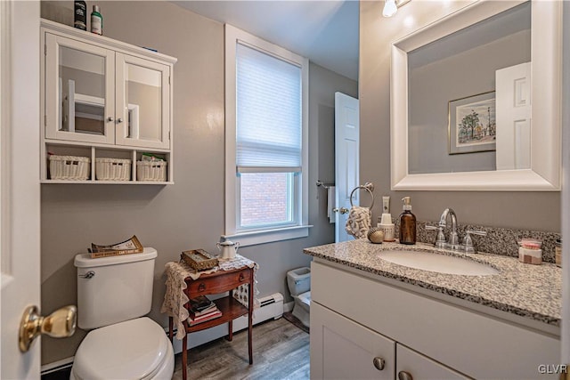 bathroom featuring hardwood / wood-style flooring, vanity, baseboard heating, and toilet