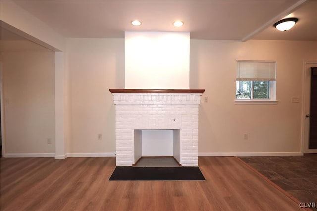 unfurnished living room featuring dark hardwood / wood-style flooring and a brick fireplace