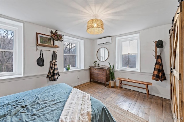 bedroom featuring hardwood / wood-style flooring, a barn door, and a wall mounted AC