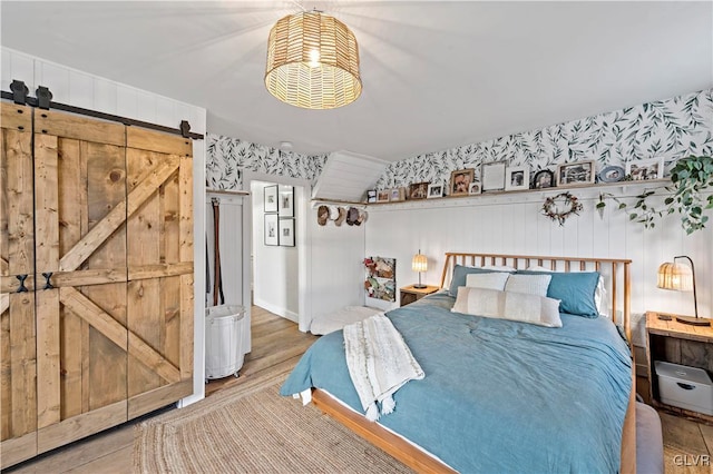 bedroom with wood-type flooring and a barn door