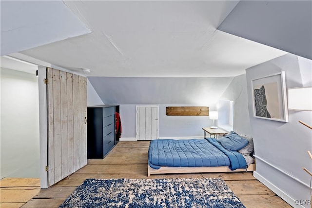 bedroom featuring lofted ceiling and light wood-type flooring