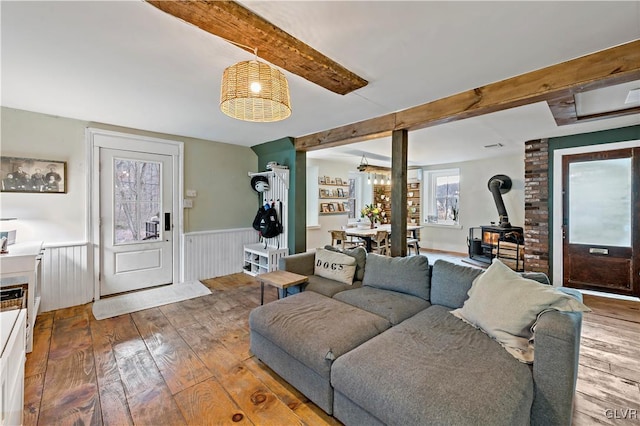 living room with hardwood / wood-style floors, beamed ceiling, and a wood stove