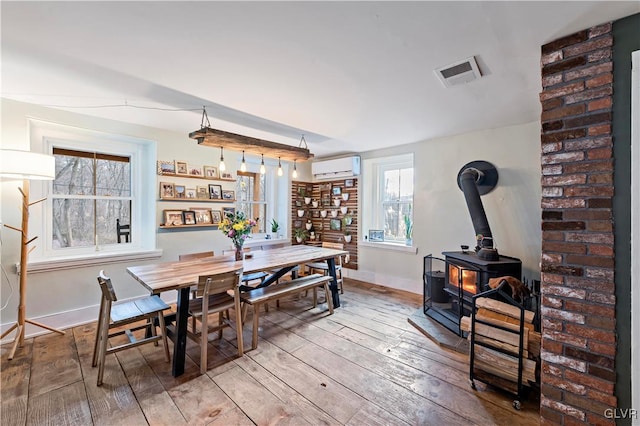 dining room featuring hardwood / wood-style floors, an AC wall unit, and a wood stove