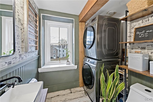 clothes washing area with stacked washer / drying machine and sink