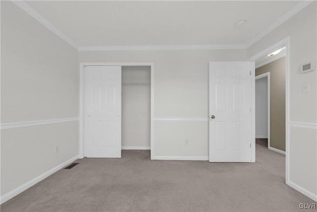 unfurnished bedroom with crown molding, a closet, and light carpet