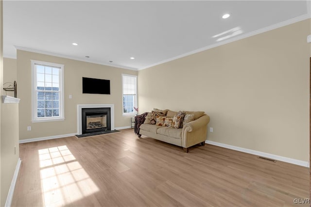 living room with ornamental molding, a healthy amount of sunlight, and light wood-type flooring