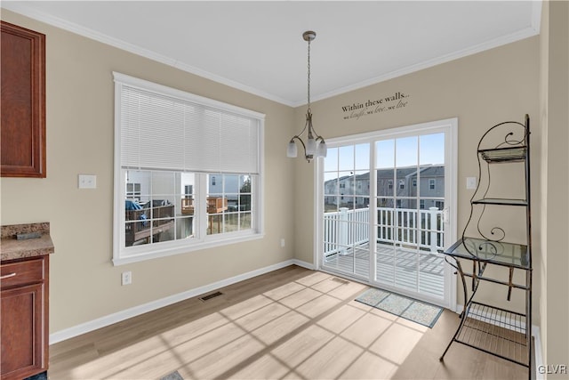 unfurnished dining area featuring crown molding, an inviting chandelier, and light wood-type flooring