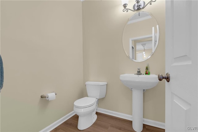 bathroom with hardwood / wood-style flooring, crown molding, and toilet