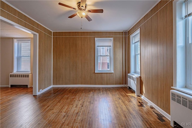 unfurnished room with ceiling fan, radiator, and light hardwood / wood-style flooring