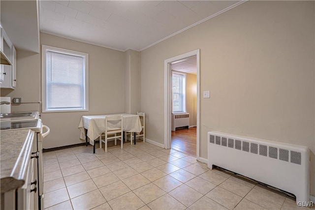 kitchen with ornamental molding, radiator, white cabinets, and electric stove