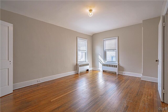 unfurnished room with radiator heating unit and hardwood / wood-style floors