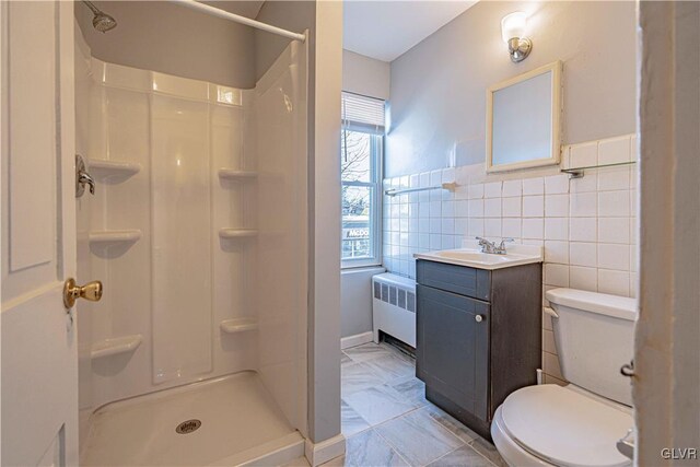 bathroom with radiator, tile walls, vanity, a shower, and toilet