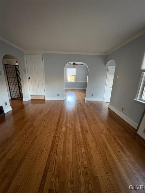 unfurnished living room with wood-type flooring, ornamental molding, and ceiling fan