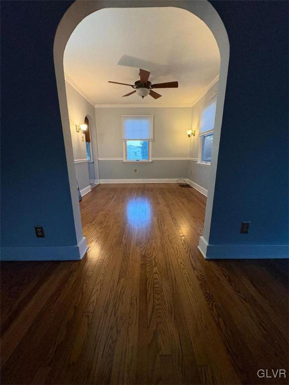 unfurnished living room with crown molding, dark hardwood / wood-style floors, and ceiling fan