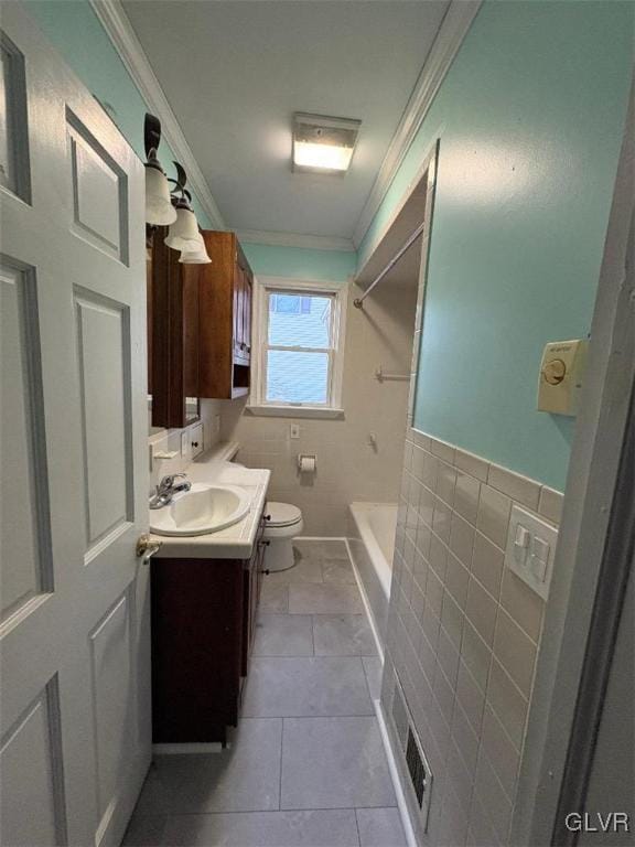 bathroom featuring toilet, tile walls, ornamental molding, vanity, and tile patterned flooring