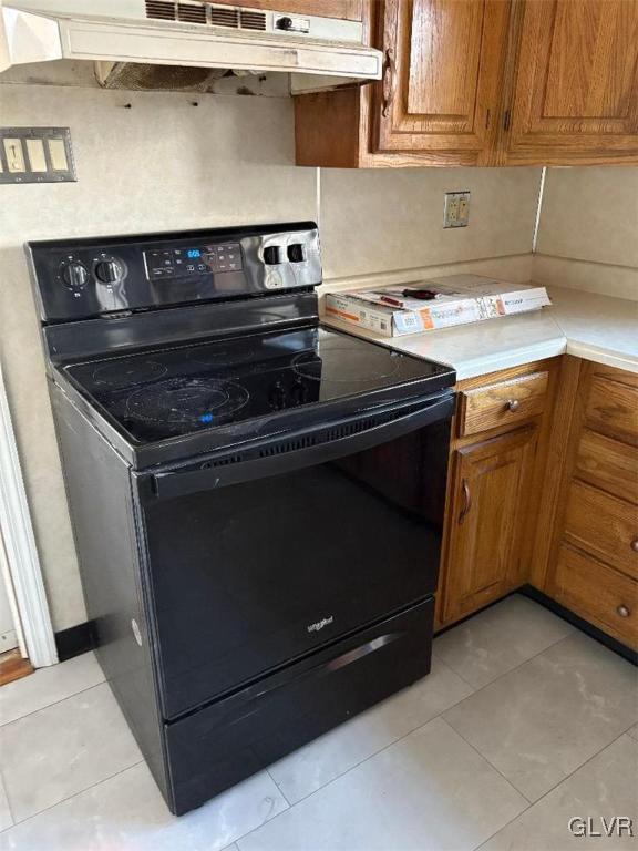 kitchen with black electric range oven and light tile patterned flooring