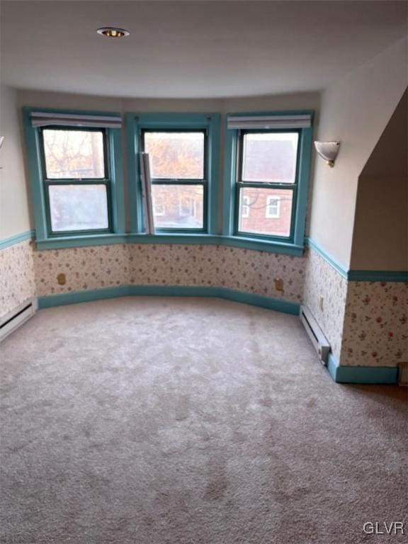 carpeted spare room featuring a baseboard heating unit