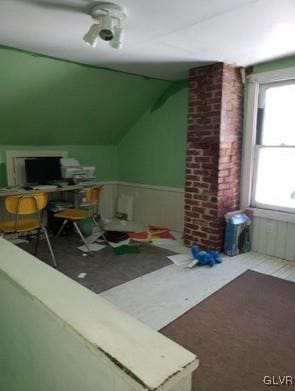 additional living space with brick wall, plenty of natural light, and lofted ceiling